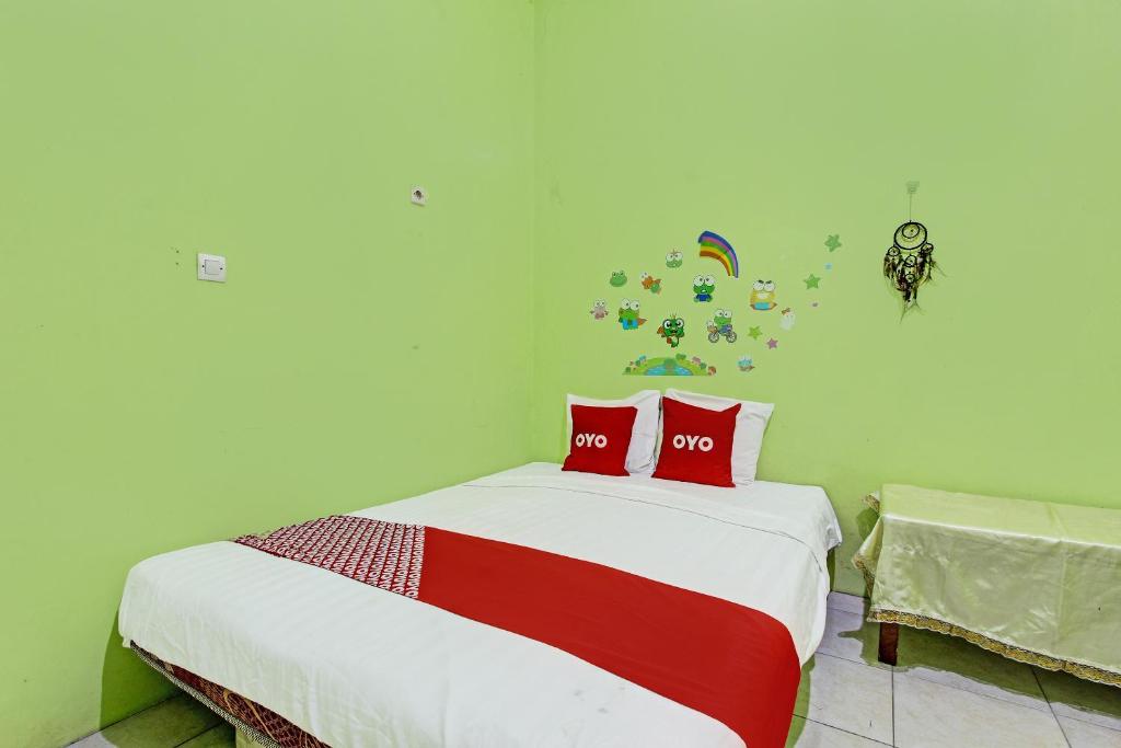 a bedroom with a bed with two red pillows at OYO 92467 Cahyo Kost 1 in Semarang