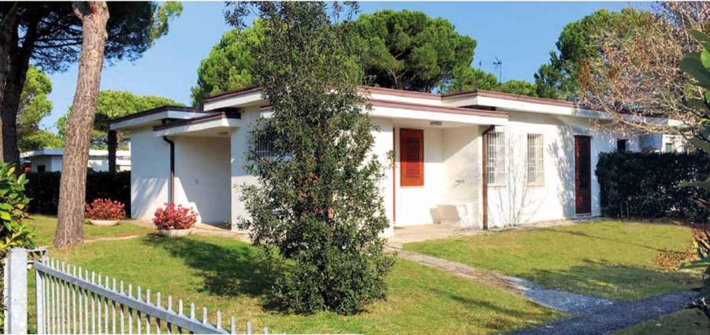 a white house with a fence in front of it at Holiday home in Bibione 41086 in Bibione