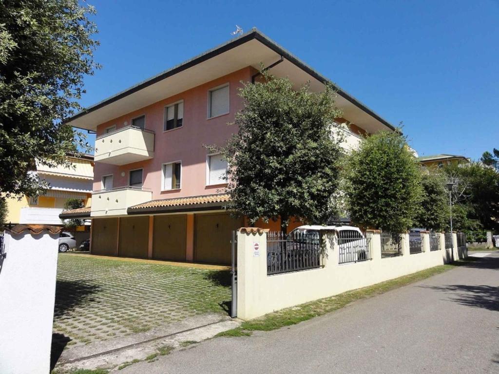 une maison rose avec une clôture devant elle dans l'établissement Apartments in Bibione 24607, à Bibione