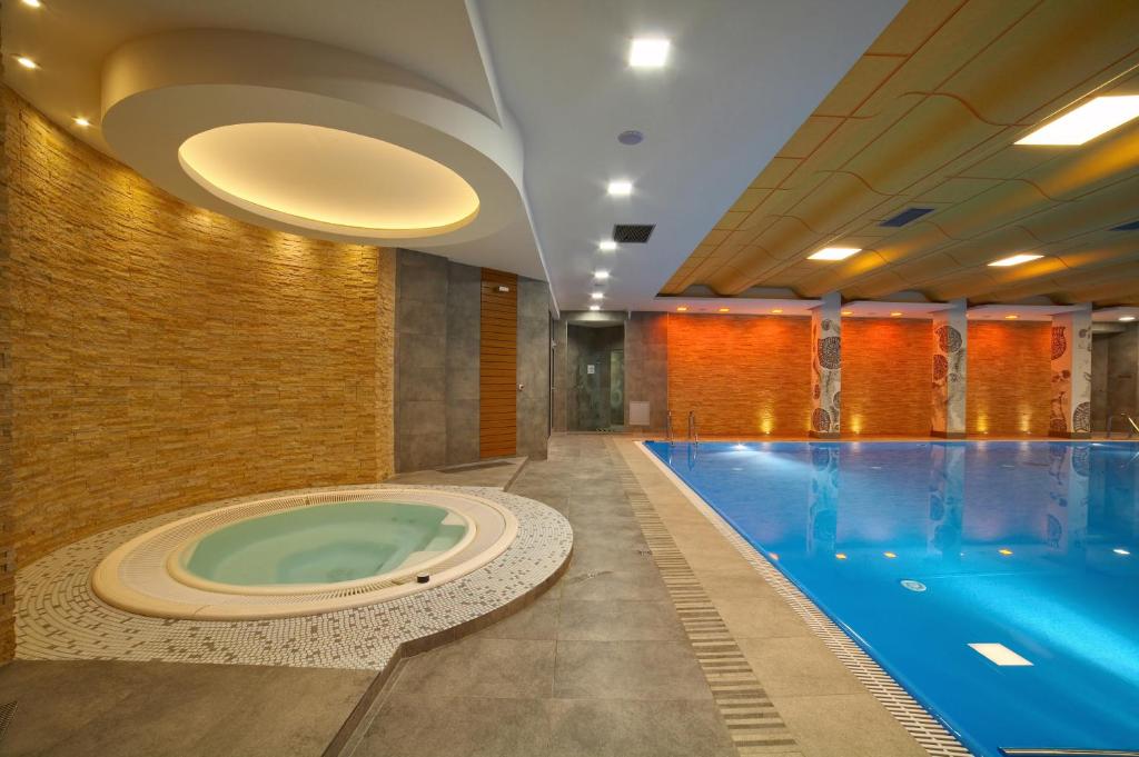 uma piscina com banheira de hidromassagem num quarto de hotel em Hotel Perła Bieszczadów Geovita em Czarna