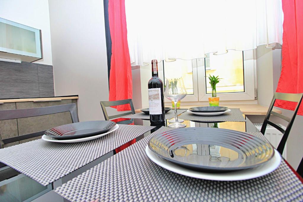 a dining table with plates and a bottle of wine at Apartamenty Jozefa Kazimierz in Krakow