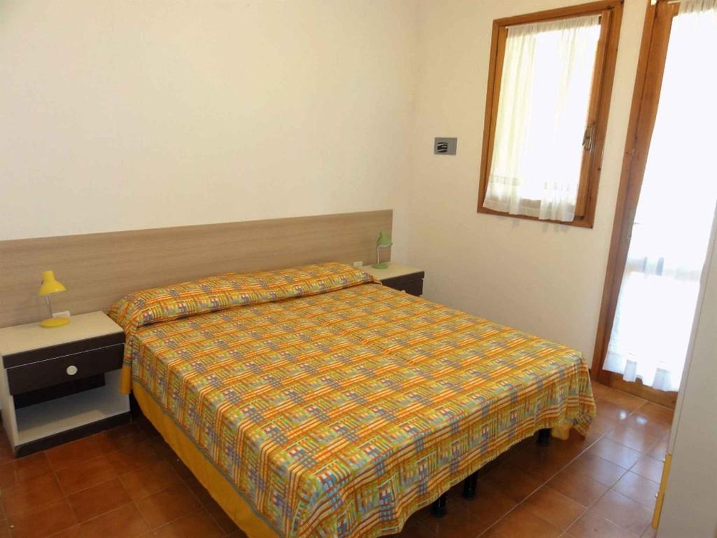 Schlafzimmer mit einem Bett, einem Tisch und einem Fenster in der Unterkunft Holiday home in Bibione 38311 in Bibione