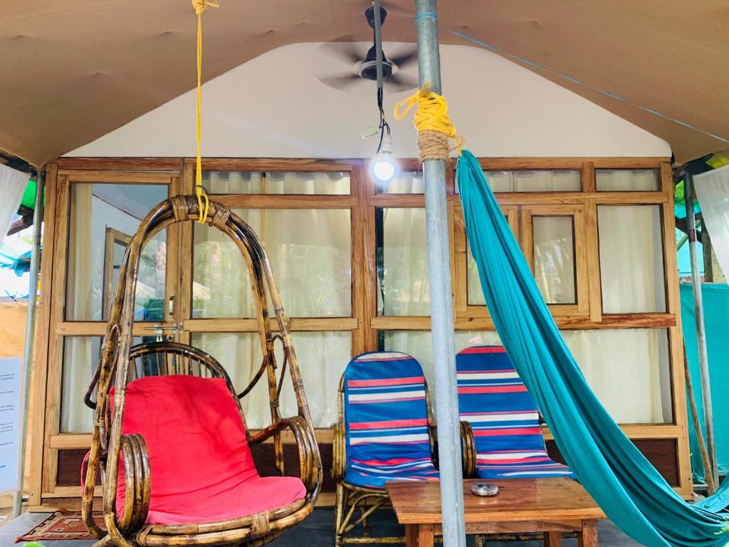 a room with chairs and a hammock and a table at Lacto Cressida Huts in Palolem