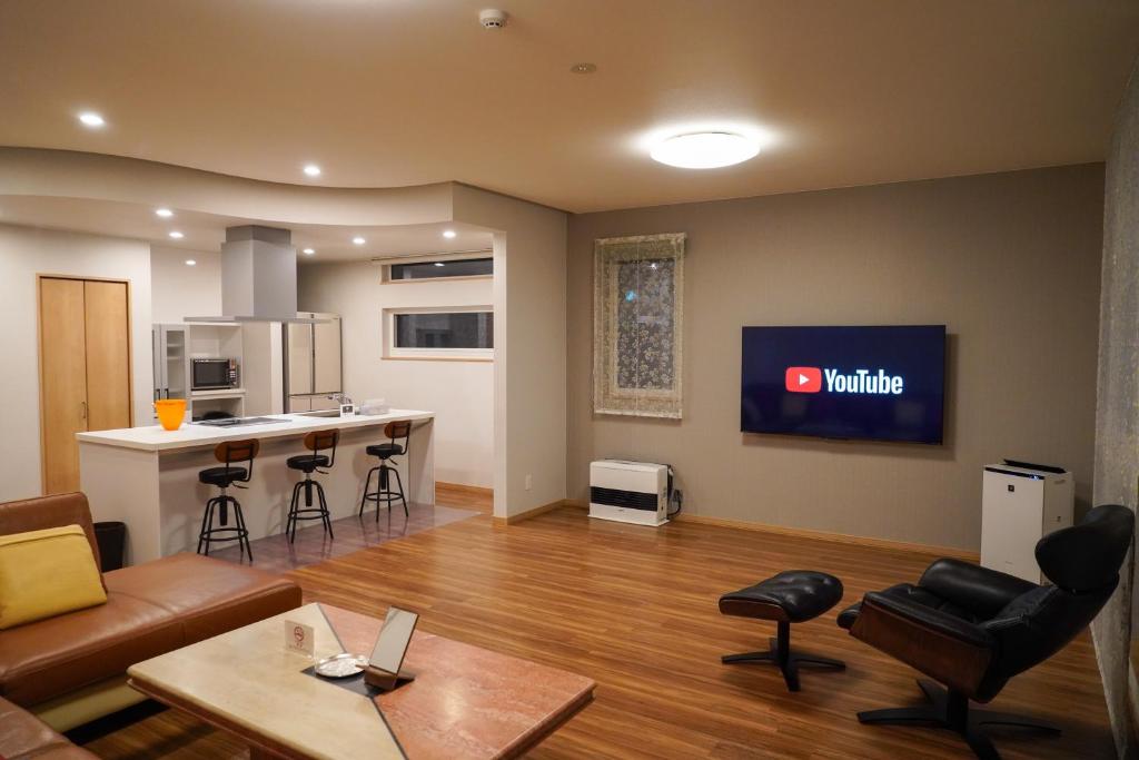 a living room with a couch and a kitchen at Hakodate MOTOMACHI guesthouse in Hakodate