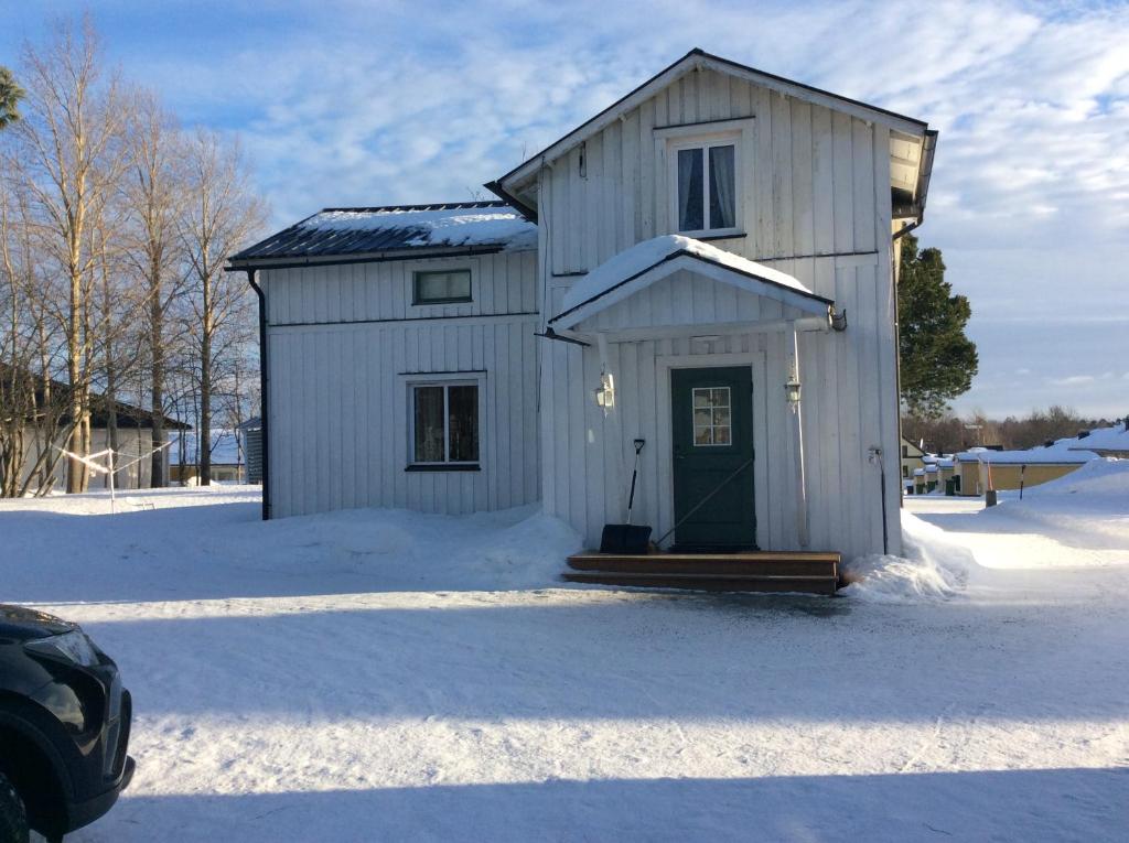 a small white building with a door in the snow at Vita villan in Haparanda