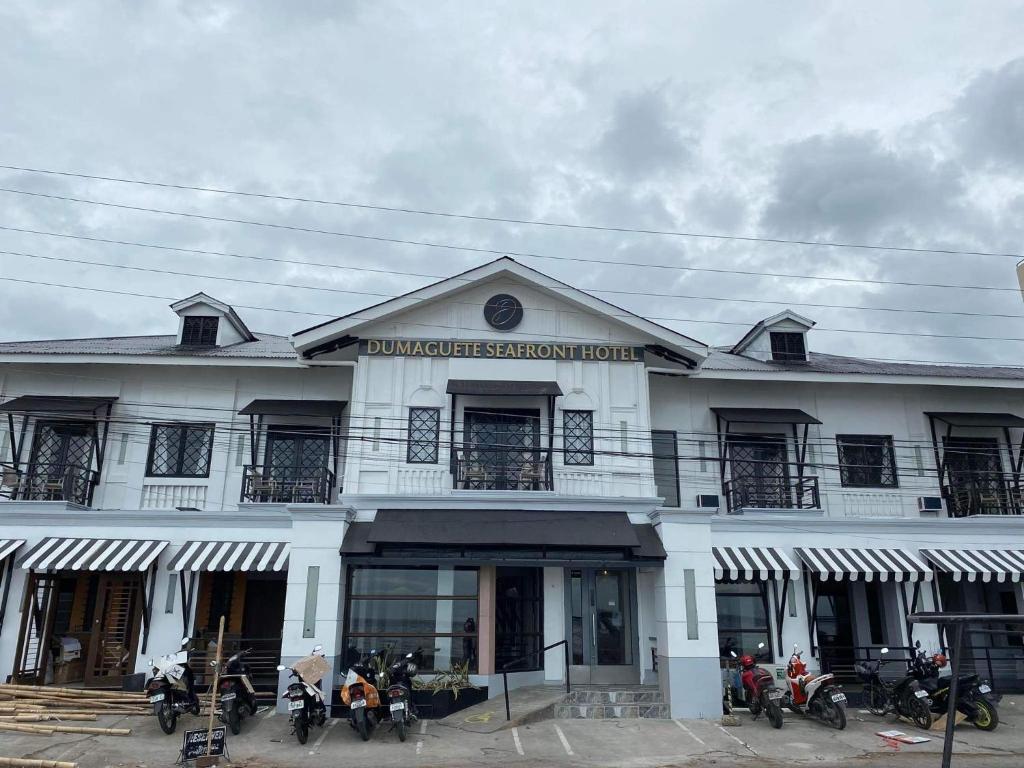 Biały budynek z motocyklami zaparkowanymi przed nim w obiekcie Dumaguete Seafront Hotel w mieście Dumaguete