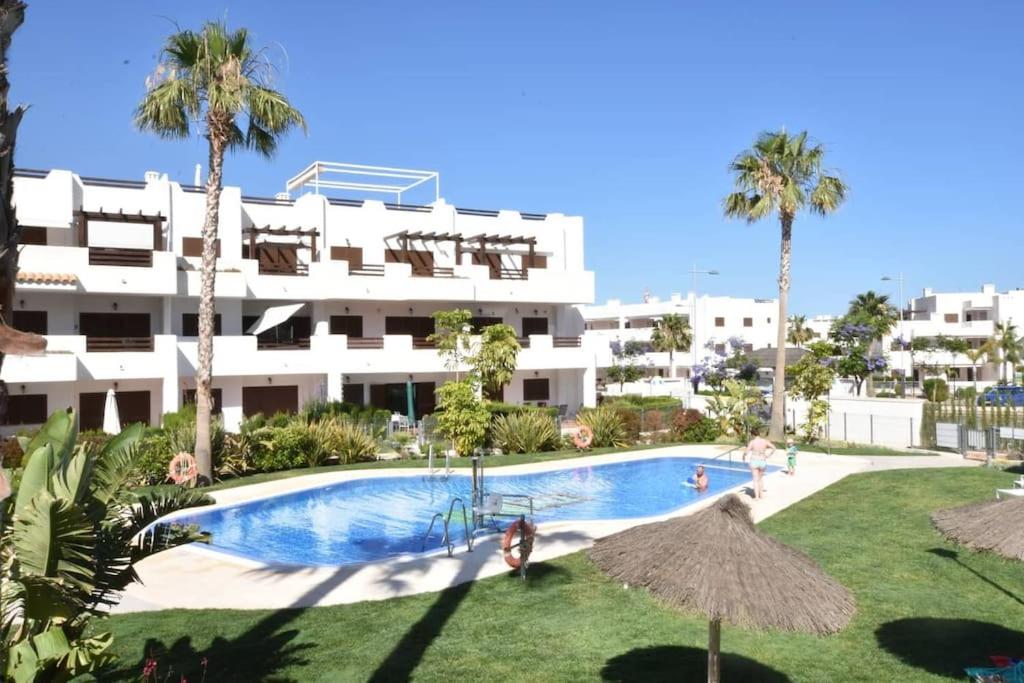 ein großes Apartmenthaus mit einem Pool und Palmen in der Unterkunft Apartamento Perdiz. Perfecto. in San Juan de los Terreros