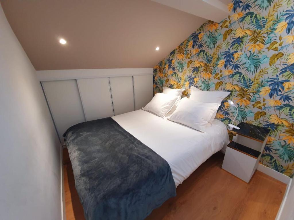 una camera da letto con un letto bianco e carta da parati floreale di Stop Chez M Select Saga # Qualité # Confort # Simplicité a Saint-Fons