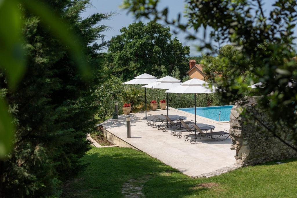 a swimming pool with umbrellas and lounge chairs and a swimming pool at Heritage Hotel San Rocco in Brtonigla