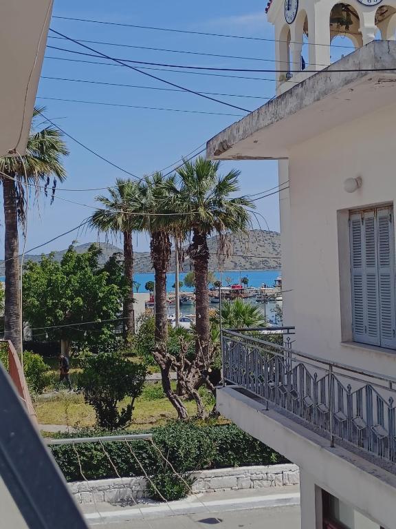 a balcony of a building with palm trees and the ocean at Kelly's Urban Apartment in Elounda
