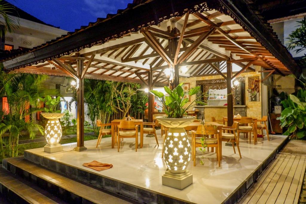 a patio with a table and chairs under a pergola at Puri Panca Jaya Hotel in Seminyak