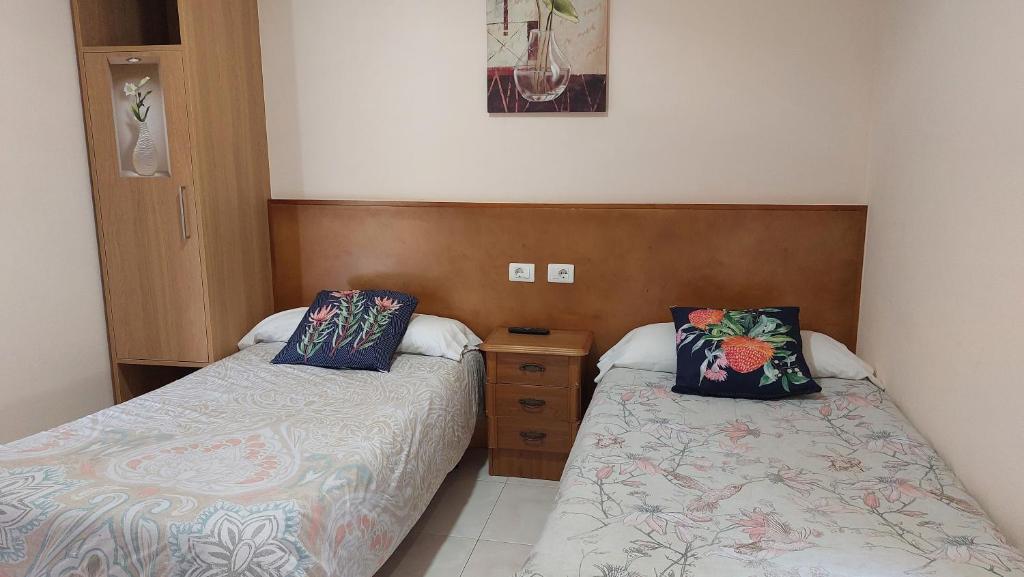 La LagunaにあるAlbergue la escuelaのベッドルーム1室(ベッド2台、木製ヘッドボード付)