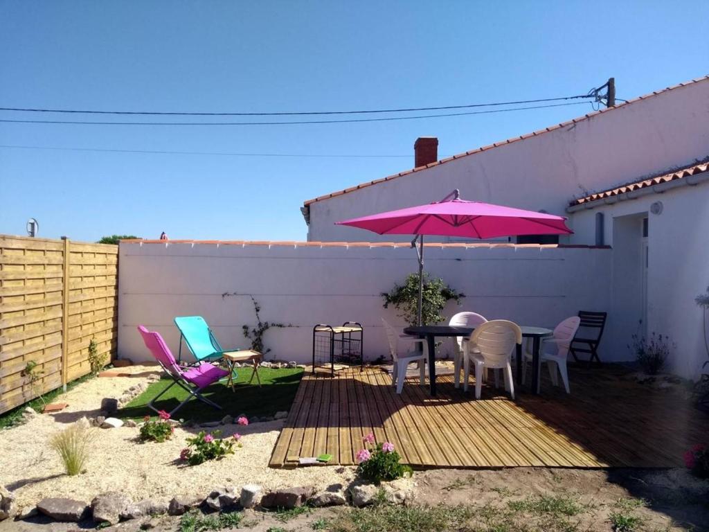 een patio met een tafel en een roze parasol bij Maison La Guérinière, 2 pièces, 4 personnes - FR-1-224B-727 in La Guérinière