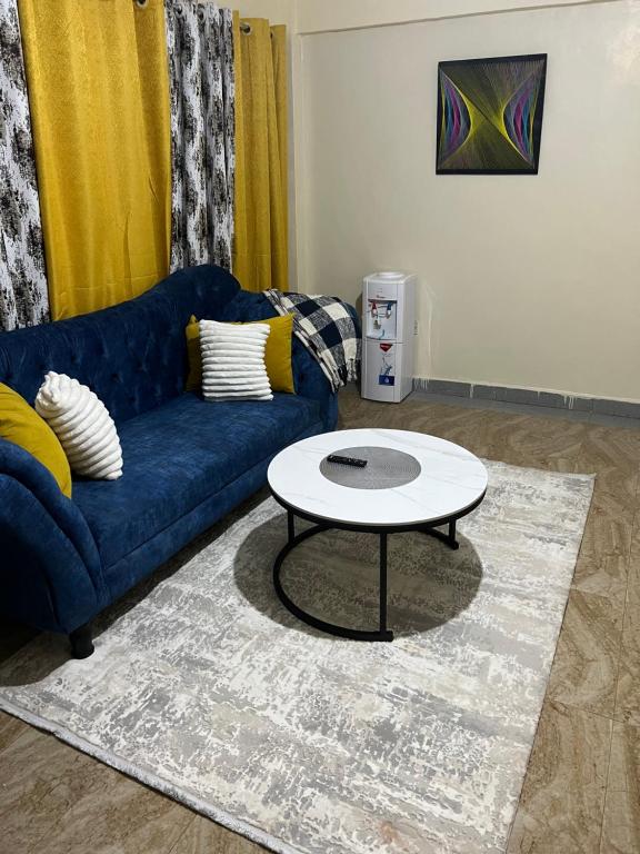 Cozy 1br apartment in King’ong’o-Nyeri في نيري: غرفة معيشة مع أريكة زرقاء وطاولة