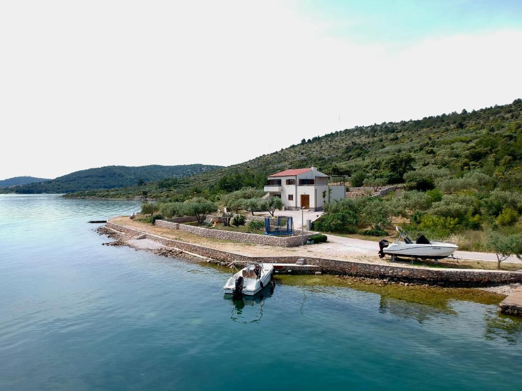 un pequeño barco en el agua junto a una casa en Sibenik Boats, en Raslina