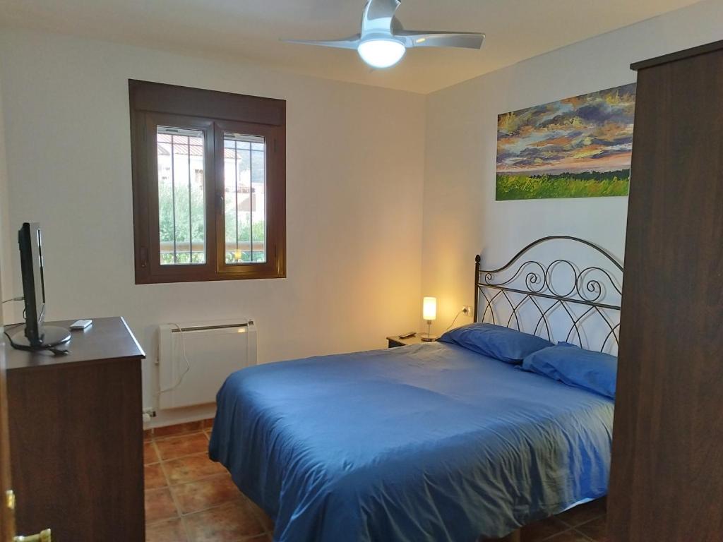 1 dormitorio con 1 cama azul y ventilador de techo en Los Olivos de Fondon, en Fondón
