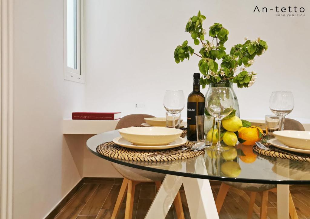 ein Esszimmer mit einem Glastisch mit Weingläsern in der Unterkunft An-tetto in Noto