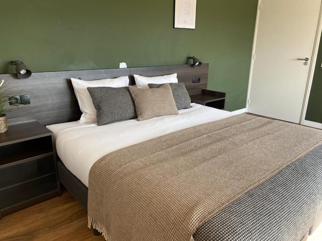 1 dormitorio con 1 cama grande con sábanas y almohadas blancas en Buitenplaats de Luwte, en Zwolle
