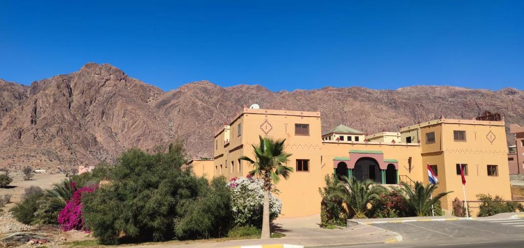 a large yellow building with mountains in the background at Auberge Kasbah Chez Amaliya in Tafraoute