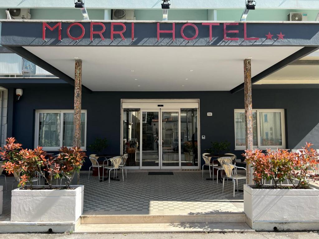 een hotel met tafels en stoelen voor een gebouw bij Hotel Morri - il BIBLIHOTEL in Riccione