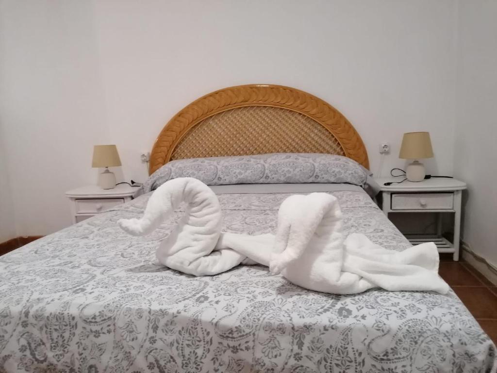 uma cama com duas toalhas brancas em Habitación matrimonial en un bajo baño compartido Areas compartidas em Abades