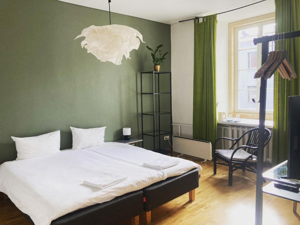 sypialnia z łóżkiem, krzesłem i telewizorem w obiekcie Rooms and Suites at Bookinn B&B w Wilnie