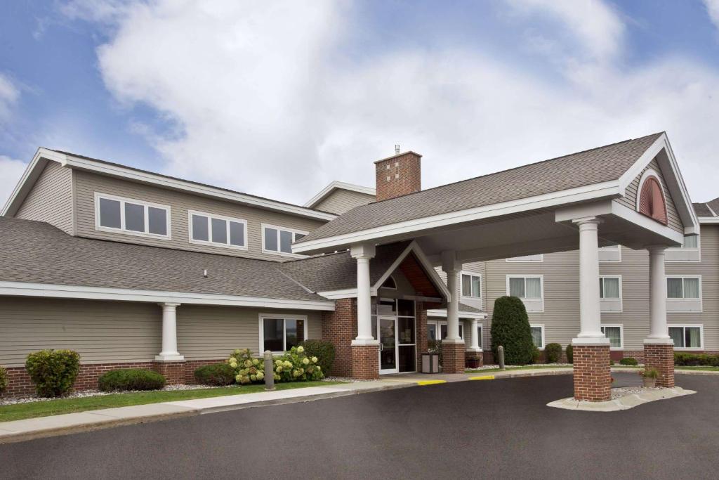 a large house with a driveway at AmericInn by Wyndham Beaver Dam in Beaver Dam