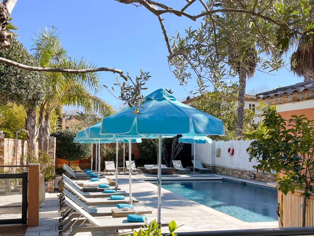 a group of lounge chairs and an umbrella next to a swimming pool at Le Mouillage in Saint-Tropez