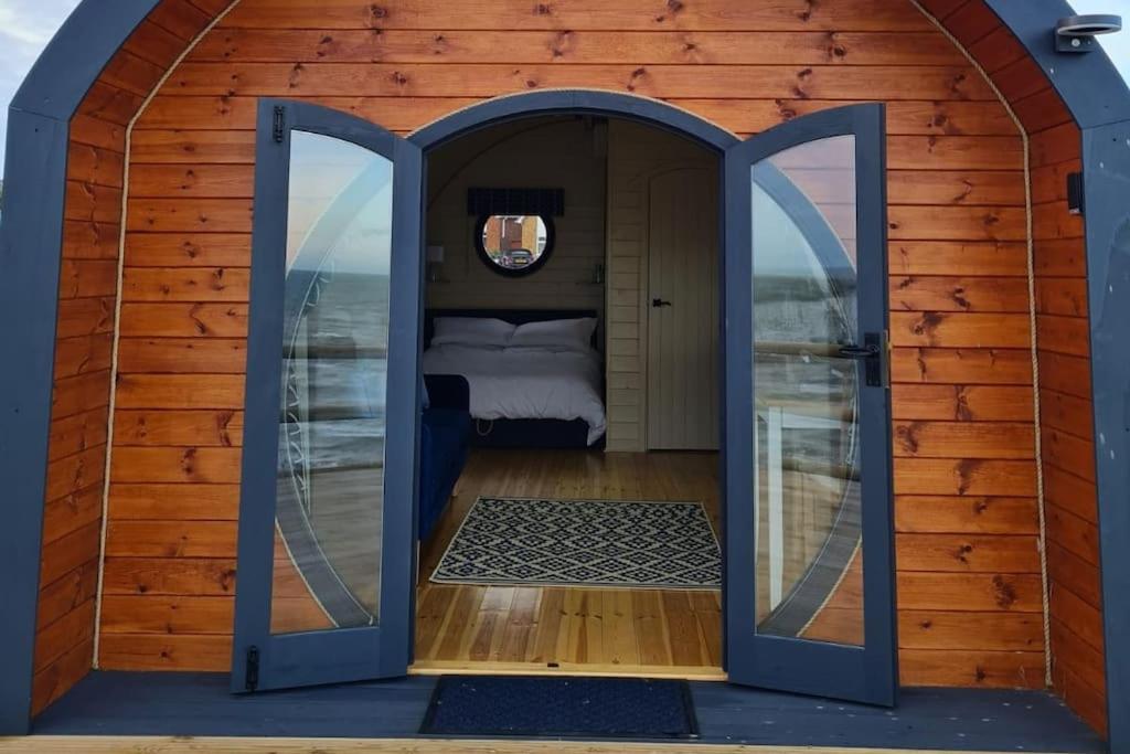 una porta aperta di una casetta con una camera da letto di Spring Tide Cliff Top Glamping Pod with direct Sea Views a Birchington