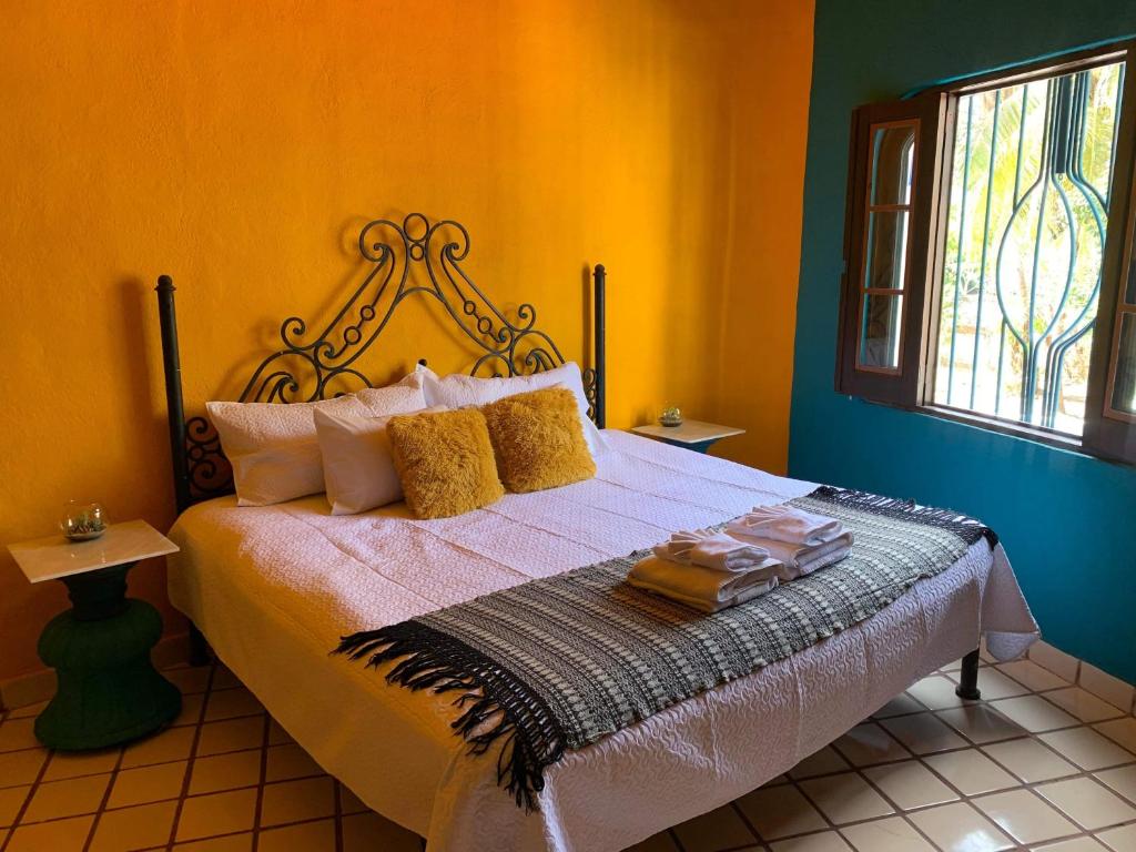 een slaapkamer met een bed met gele muren bij VILLA OASIS in Puerto Vallarta