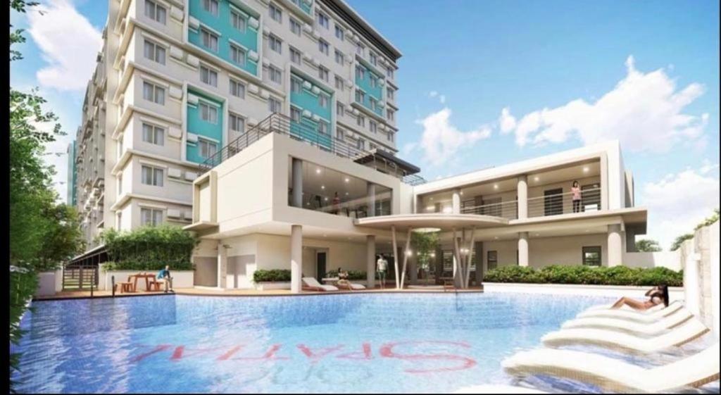 a hotel with a swimming pool in front of a building at One spatial iloilo city two bedroom condo with free Netflix wifi pool and Gym in Iloilo City