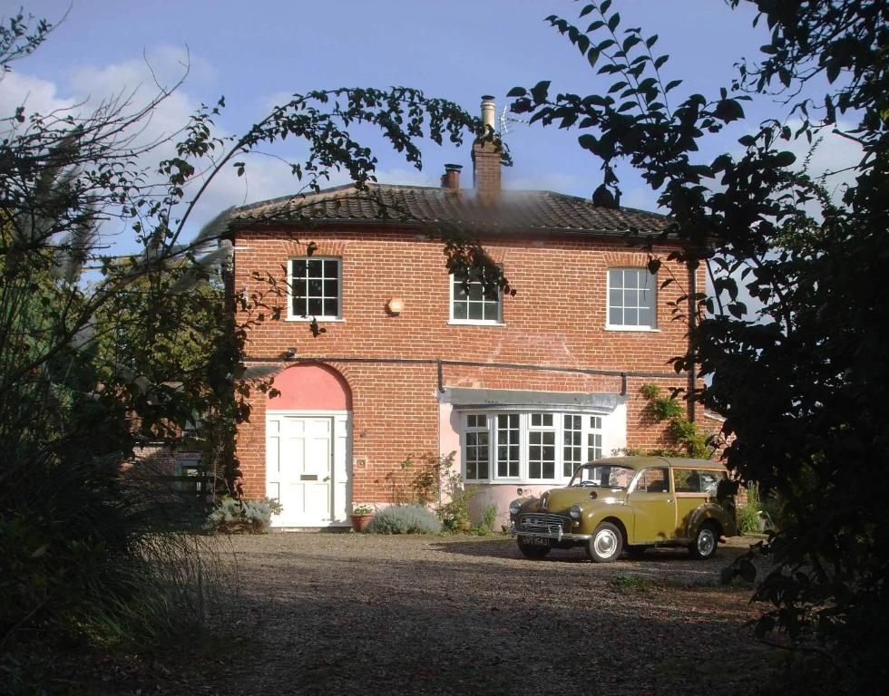 an old car parked in front of a brick house at The Old Vicarage Bed And Breakfast in Hindolveston