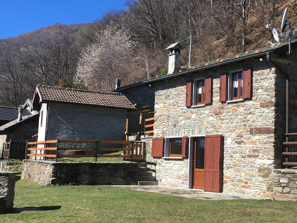 a stone building with red doors and a mountain at Chalet Buonriposo in Cremia