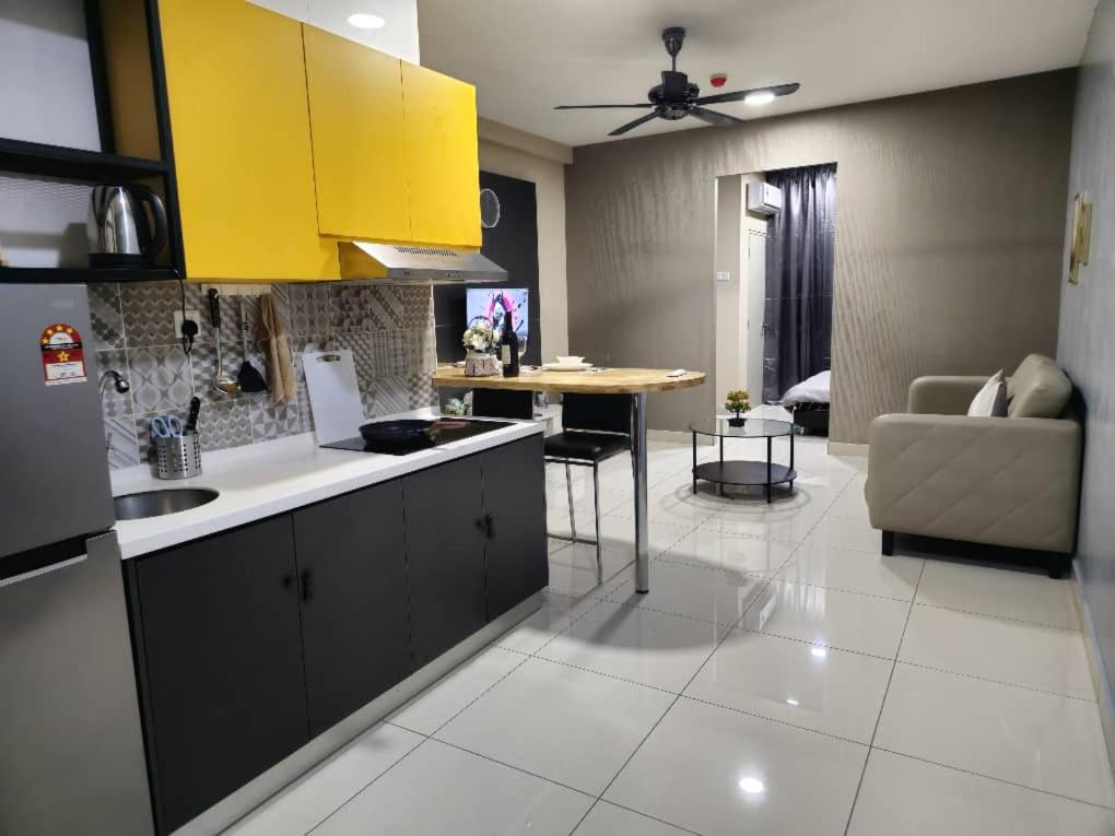 a kitchen with yellow cabinets and a living room at Liberty Arc Studio 舒适和家温暖的感觉 in Ampang