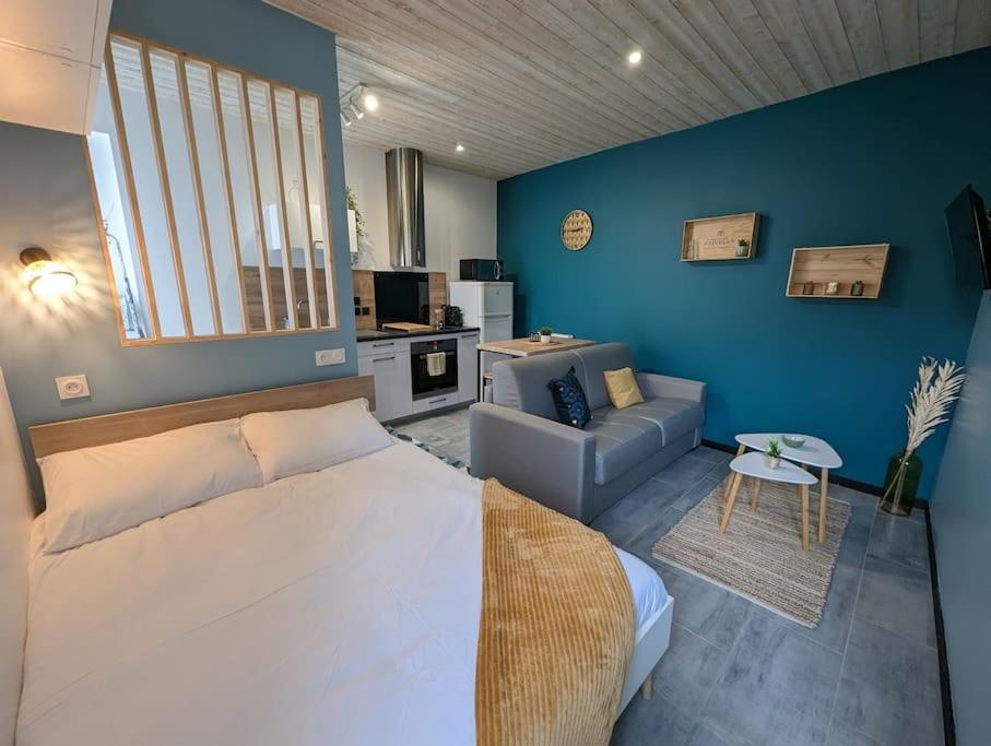 a bedroom with a bed and a living room with a couch at Le Studio Pop in Paray-le-Monial