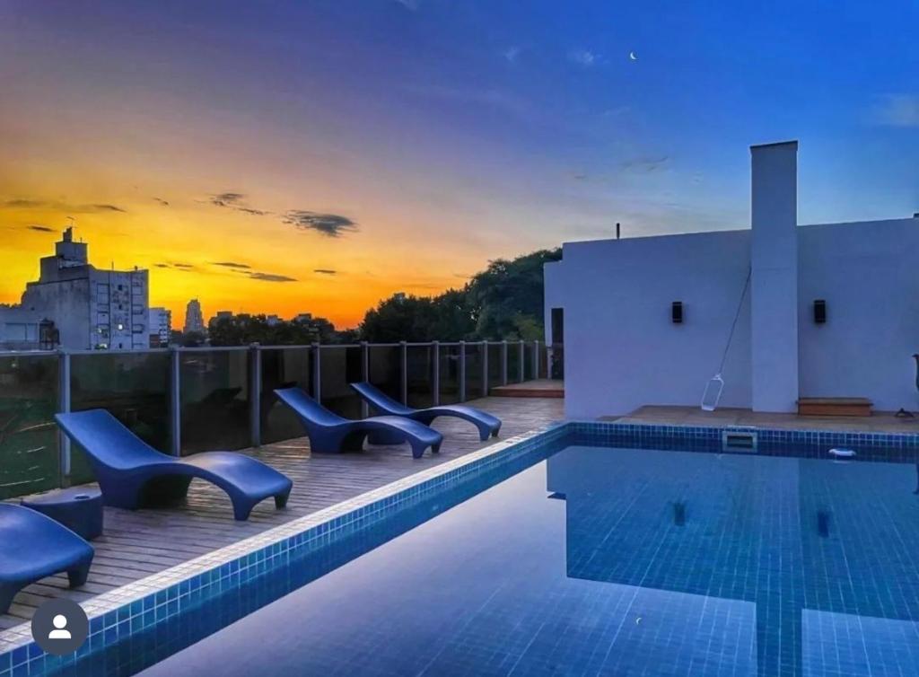 una piscina en la azotea de un edificio con puesta de sol en First Palermo Hotel en Buenos Aires
