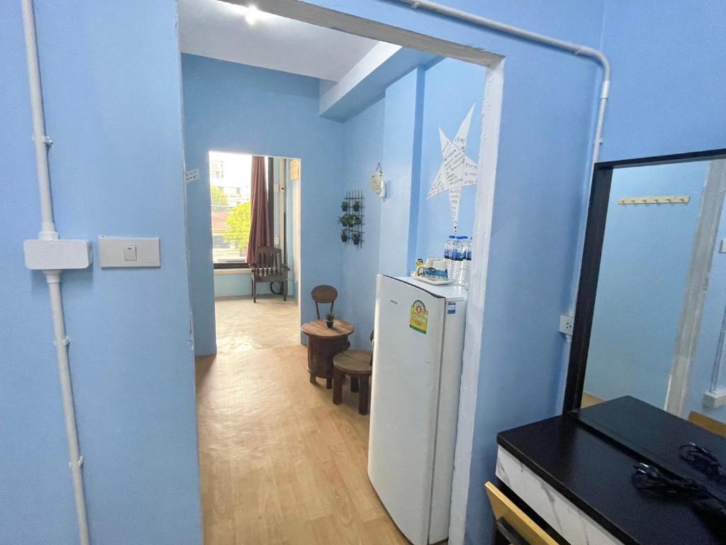 a blue room with a refrigerator and a hallway at Bake Room Hostel in Chiang Mai