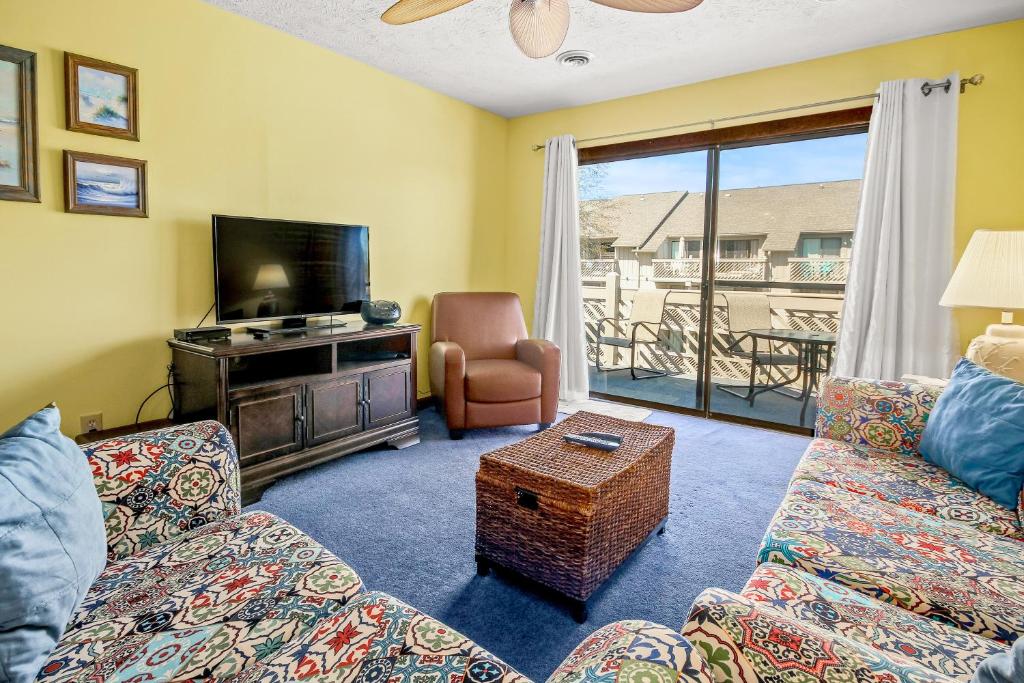 ein Wohnzimmer mit einem Sofa, einem TV und einem Stuhl in der Unterkunft Shipwatch Pointe II Q-305 in Myrtle Beach