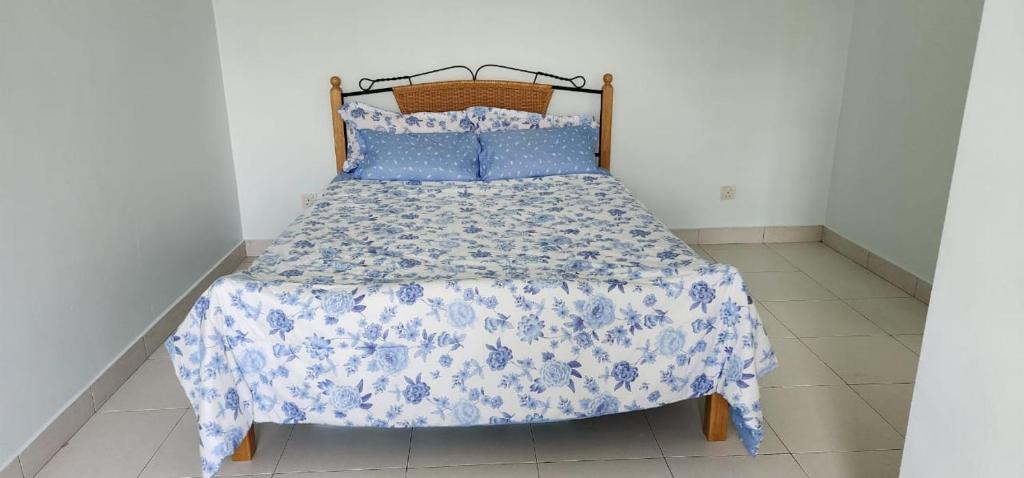 uma cama com um edredão e almofadas azuis e brancas em Bertam Homestay Kepala Batas em Kepala Batas