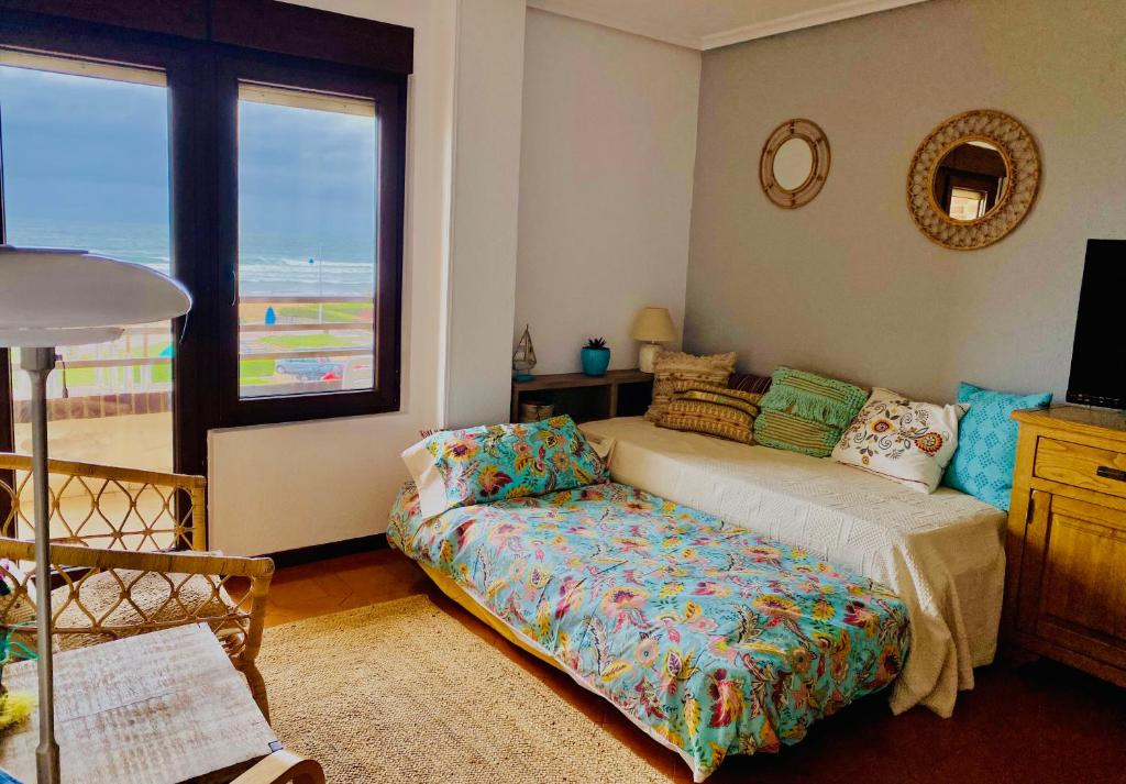 a bedroom with a bed and a couch and a window at Vistas al Mar in Somo
