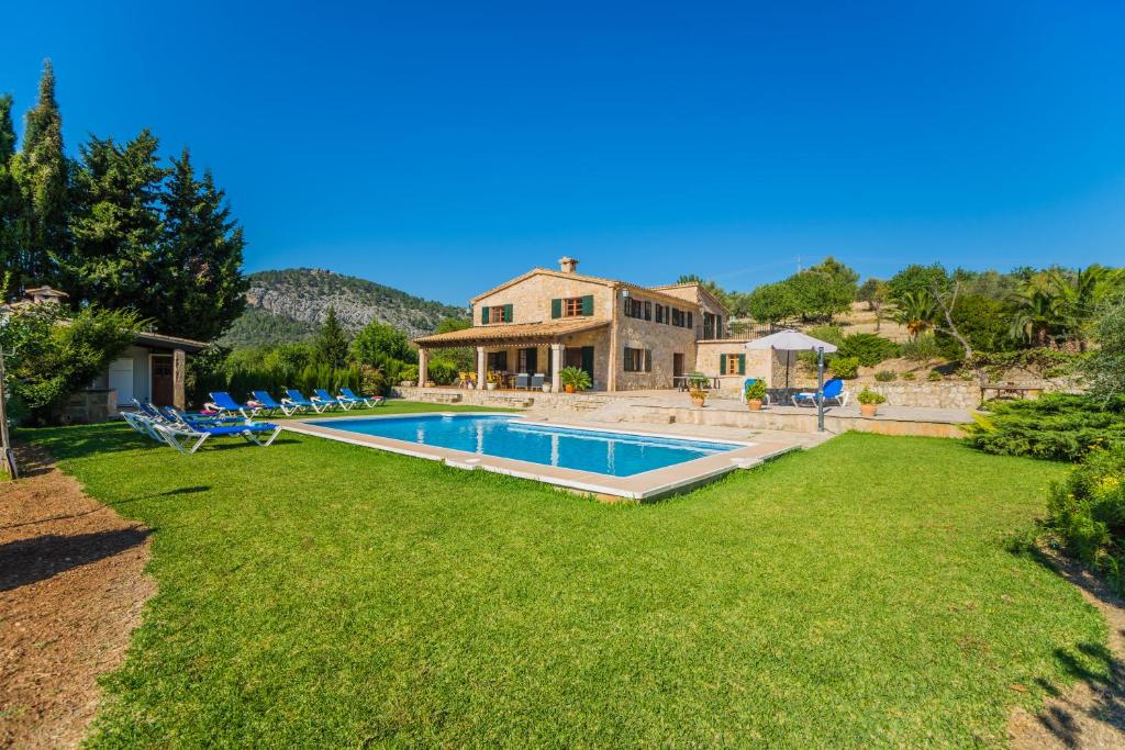 a large yard with a swimming pool in front of a house at Villa El Olivo in Pollença