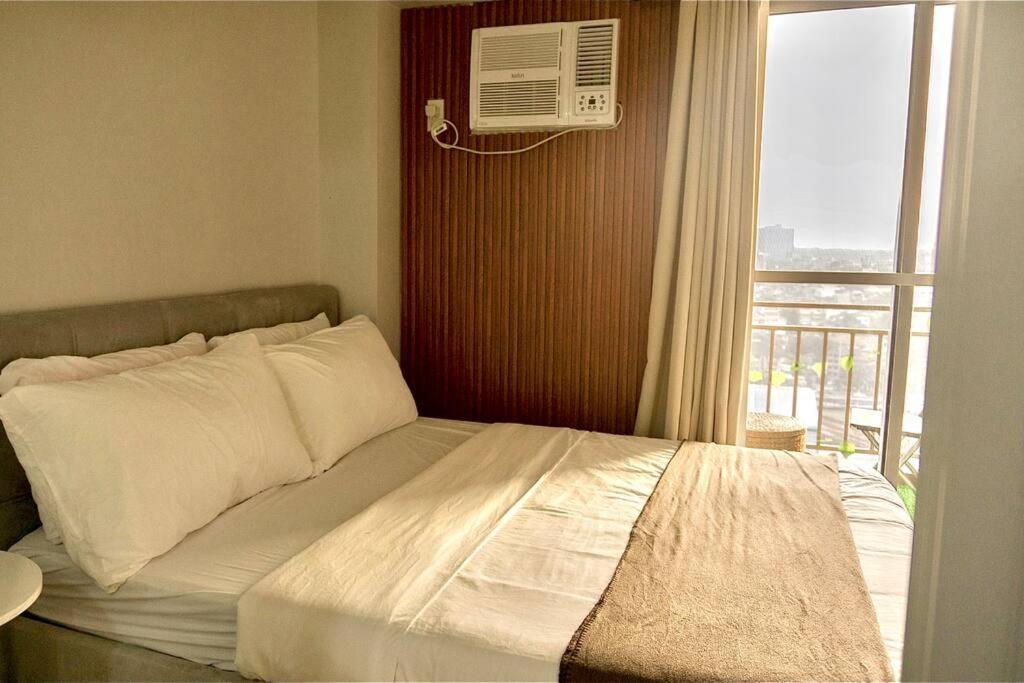 a bedroom with a bed and a window with a air conditioner at Weston 1 bedroom Unit with Balcony in Manila
