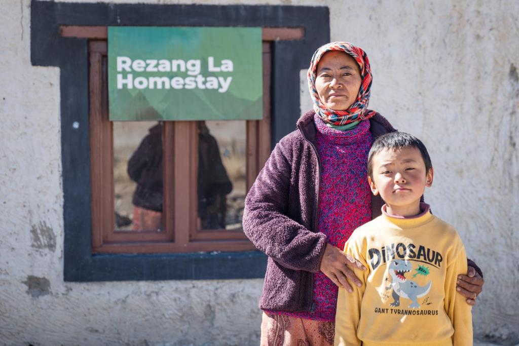 a woman and a boy standing in front of a building at RezangLa Homestay in Chushul