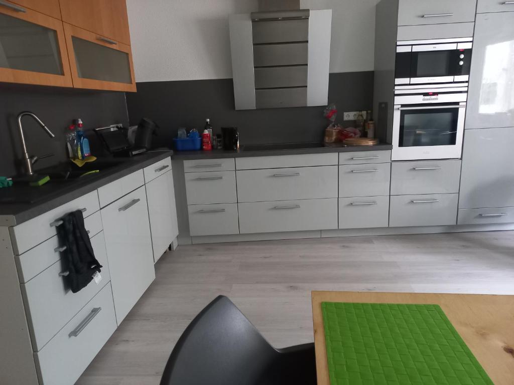 a kitchen with white cabinets and a green table at myHome in Gießen