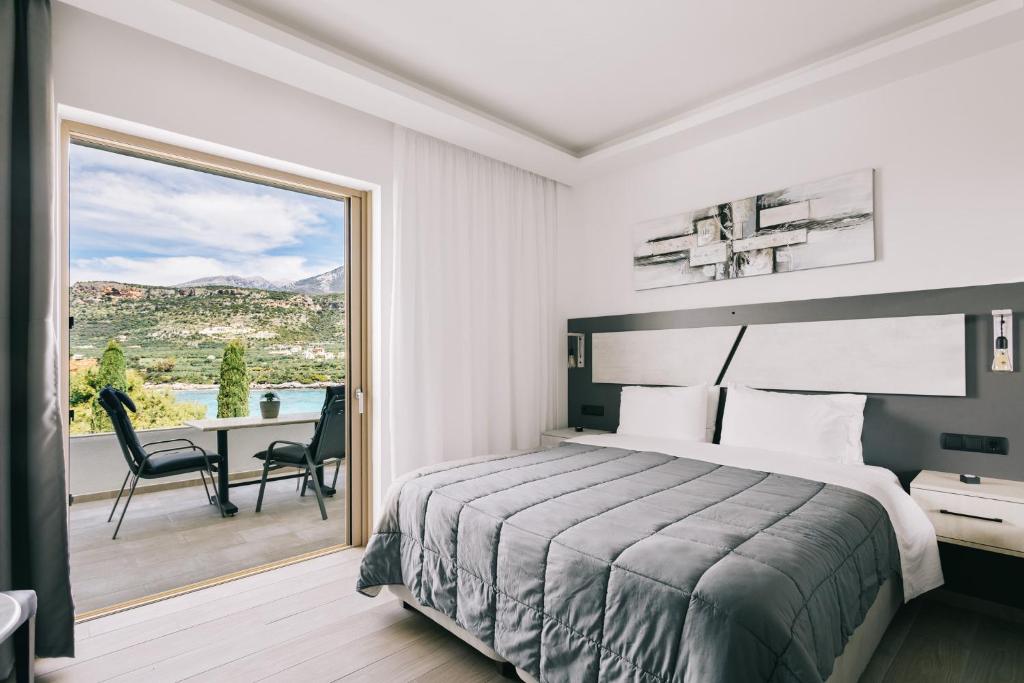a bedroom with a bed and a balcony with a table at Lighthouse Apartments in Stoupa