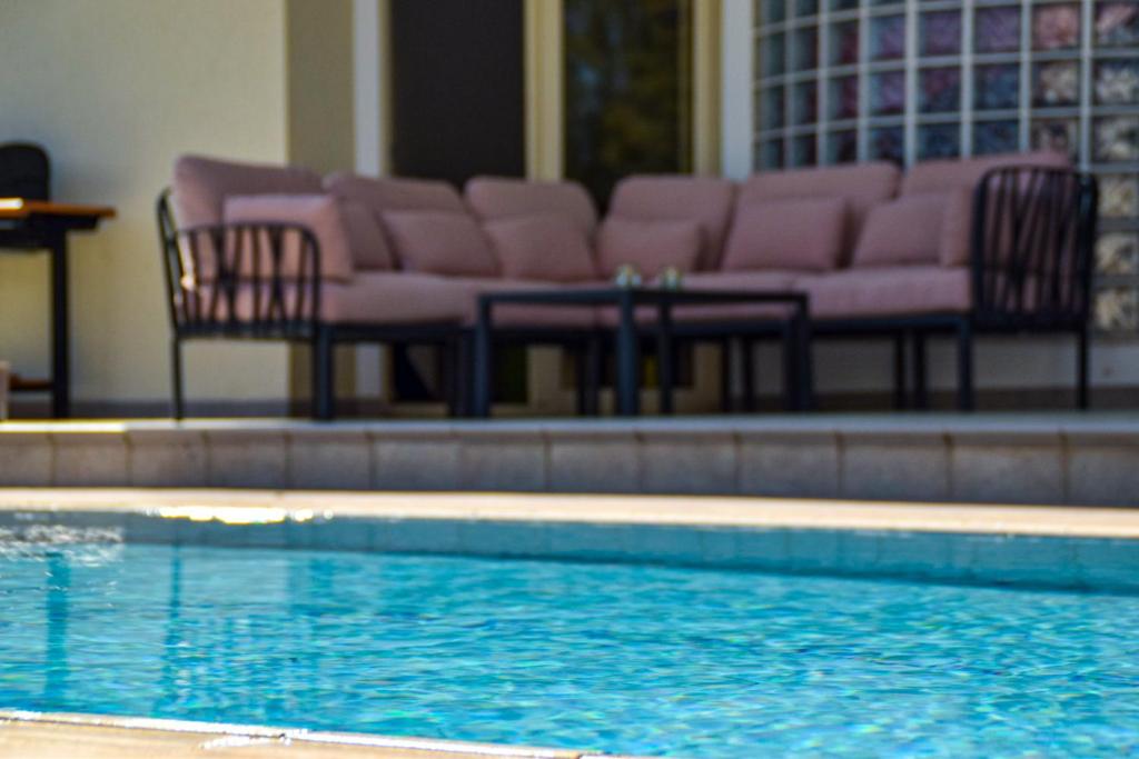 een zwembad met stoelen en een tafel en een zwembad met water bij Ilios Villa in Larnaka