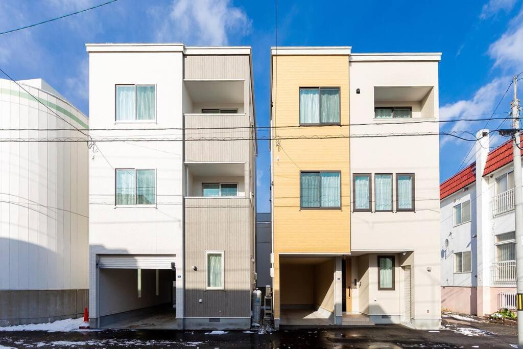 eine Reihe weißer Gebäude mit Gelb in der Unterkunft GUEST HOUSE EARTH【THE MOON & THE SUN】 in Sapporo