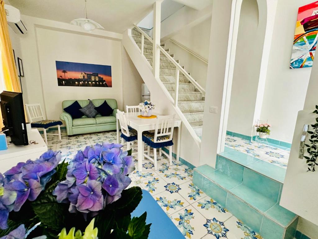 uma sala de estar com uma escada e flores roxas em Blue Apartment em Ischia