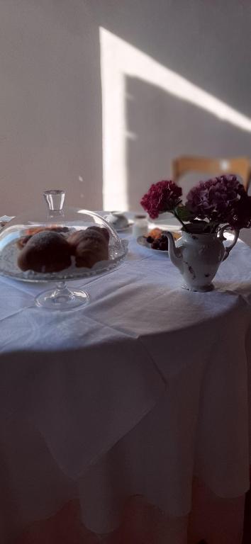 une table avec deux assiettes et un vase avec des fleurs. dans l'établissement B&B Corte Vo Grande, à Pegognaga