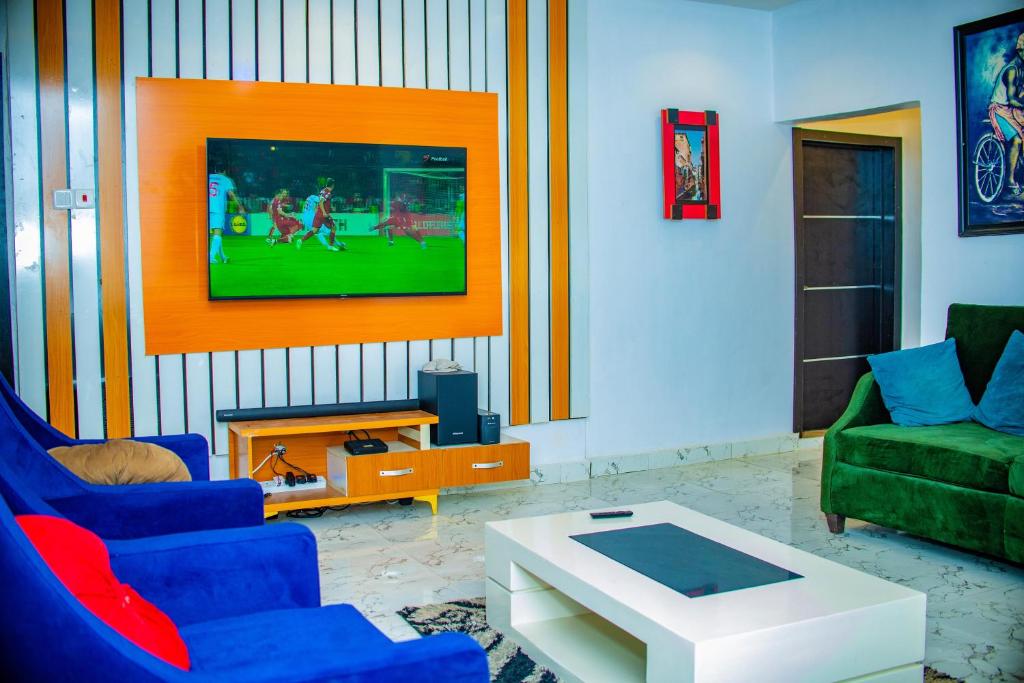 a living room with two blue chairs and a tv at Spacious 2-bed Apt With 24hrs Power+ Unlimited Wi-Fi in Lagos